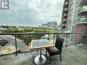 Markham (Unionville) condo for rent - A balcony with a table and chairs overlooking a parking lot and buildings.