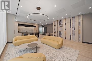 Toronto (University) condo for rent - A living room with a yellow sofa and a circular light fixture on the ceiling.