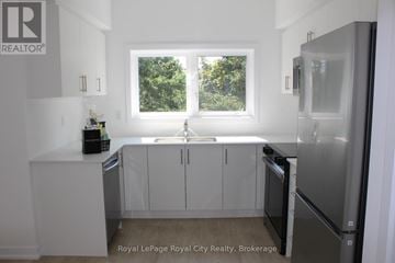 Guelph (Clairfields/Hanlon Business Park) townhouse for rent - A white kitchen with a sink and refrigerator.