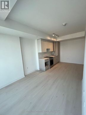 Mississauga (City Centre) condo for rent - A spacious room with a kitchenette and wooden flooring.