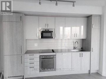 Toronto (Church-Yonge Corridor) condo for rent - A kitchen with white cabinets and a black stove top oven.