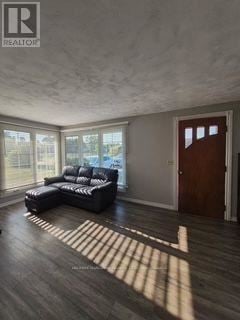 Fort Erie (Ridgeway) apartment for rent - A living room with a black leather sofa and a wooden door.