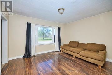 Fort Erie (Central) apartment for rent - A living room with a brown couch and a window with curtains.