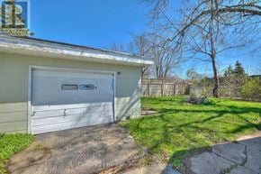 Fort Erie (Central) apartment for rent - A garage with a white door is situated in a yard with a tree and a fence.