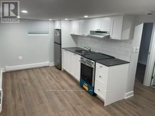 Toronto (New Toronto) apartment for rent - A kitchen with white cabinets and a black countertop.