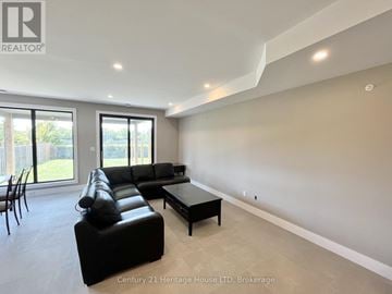 St. Catharines (Oakdale) apartment for rent - A spacious living room with a black leather sofa and a coffee table.