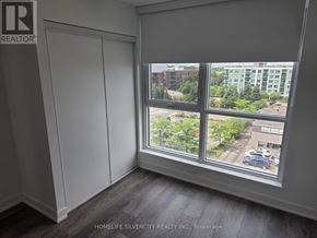 Toronto (Clairlea-Birchmount) condo for rent - A room with a large window showing a view of a parking lot and buildings outside.