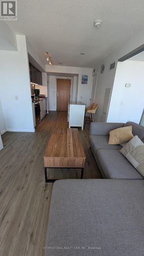 Toronto (Waterfront Communities) condo for rent - A living room with a grey couch and a wooden table.