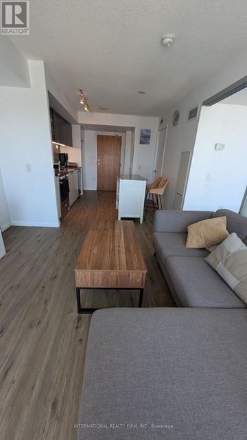 Toronto (Waterfront Communities) condo for rent - A living room with a grey couch and a wooden table.