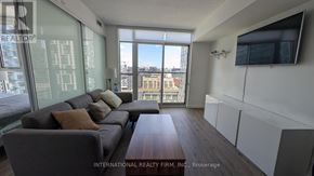 Toronto (Waterfront Communities) condo for rent - A living room with a grey couch and a flat screen TV mounted on the wall.