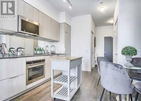 Toronto (Yonge-St. Clair) condo for rent - A modern kitchen with a white color scheme and a dining area with a grey chair.