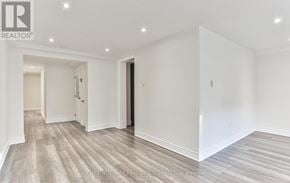 Toronto (Yonge-St. Clair) triplex for rent - A spacious room with wood flooring and white walls.