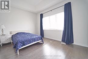 Whitby apartment for rent - A bedroom with a bed, nightstand, and window.