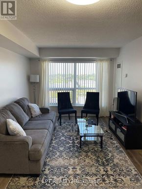 Toronto (Agincourt South-Malvern West) condo for rent - A living room with a grey couch, a black chair, a black TV and a glass coffee table.