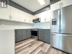 Pickering (Bay Ridges) condo for rent - A kitchen with stainless steel appliances and white cabinets.