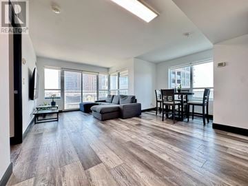 Pickering (Bay Ridges) condo for rent - A spacious living room with a grey sofa and a wooden floor.