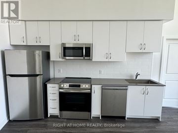 Oshawa (Windfields) condo for rent - A kitchen with white cabinets and a stainless steel refrigerator.
