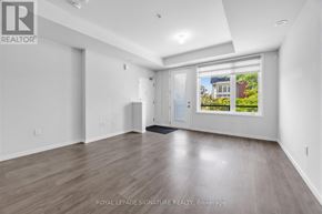 Pickering (Duffin Heights) townhouse for rent - A spacious room with wooden flooring and white walls, with a window showing an outdoor view.