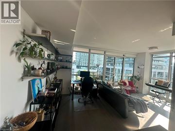 Etobicoke condo for rent - A living room with a couch, a chair, a table, and a large window.