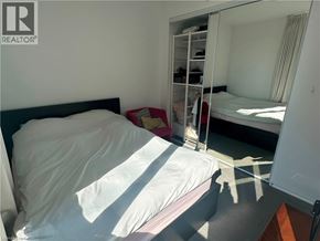 Etobicoke condo for rent - A bedroom with a bed, a mirror, and a wardrobe.