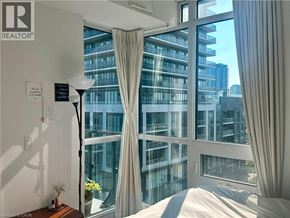 Etobicoke condo for rent - A bedroom with a large window overlooking a cityscape.