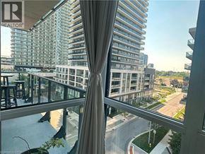 Etobicoke condo for rent - A view from a window of a tall building with a curtain in the foreground.