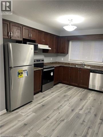 Kitchener townhouse for rent - A kitchen with a stainless steel refrigerator and wooden cabinets.