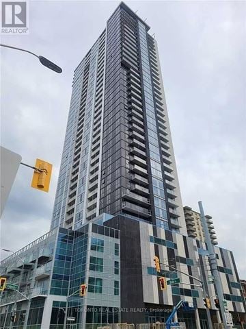 Kitchener condo for rent - A tall building under construction with a crane in front of it.