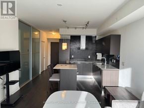 Toronto (Lansing-Westgate) condo for rent - A modern kitchen with dark wood floors and a black countertop.