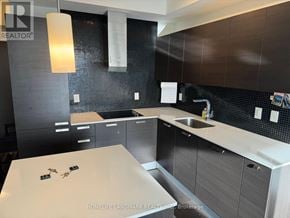 Toronto (Lansing-Westgate) condo for rent - A modern kitchen with dark brown cabinets and a white countertop.