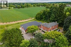 Ancaster apartment for rent - A red brick house with a black roof is surrounded by green trees.