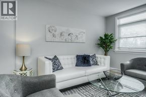 Kitchener apartment for rent - A living room with a white couch, grey armchair, and a glass coffee table.
