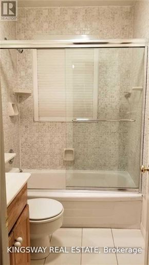 Oakville (Fd Ford) apartment for rent - A white toilet sits in a bathroom with a glass shower door.