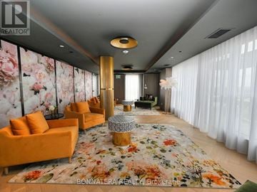 Oakville (Go Glenorchy) condo for rent - A living room with orange chairs and a floral rug.