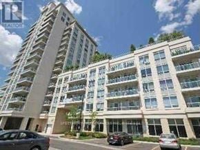 Toronto (Long Branch) condo for rent - A tall residential building with multiple balconies and cars parked in front.