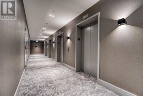 Toronto (South Parkdale) condo for rent - A hallway with elevators on the right side and a REALTOR sign on the wall.
