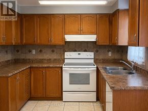 Brampton (Snelgrove) apartment for rent - A kitchen with wooden cabinets and a white stove top oven.