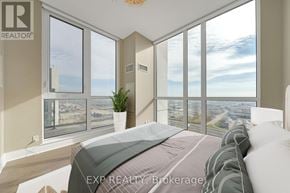 Toronto (Islington-City Centre West) condo for rent - A bedroom with a large bed and a view of the city through the windows.