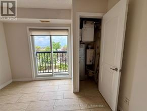Hamilton (Meadowlands) condo for rent - A room with a sliding glass door leading to a balcony and a kitchen area with a refrigerator, sink, and cabinets.