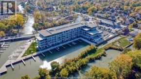 Tecumseh condo for rent - A large building with a waterfront is surrounded by trees.