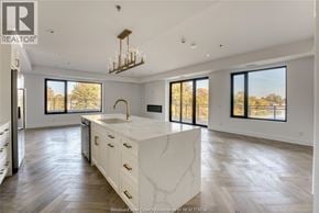 Tecumseh condo for rent - A large, modern kitchen with a central island and a view of trees outside the windows.