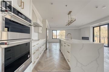 Tecumseh condo for rent - A kitchen with white cabinets and a marble countertop.