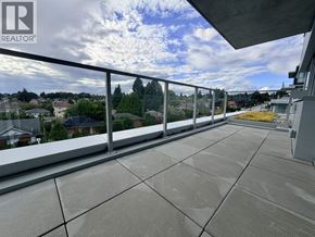 Vancouver apartment for rent - A balcony with a metal railing and a view of houses and trees.