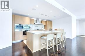Vancouver apartment for rent - A modern kitchen with a large island and white chairs.