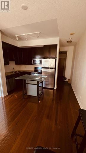 Toronto (University) condo for rent - A kitchen with dark wood cabinets and a white fridge.