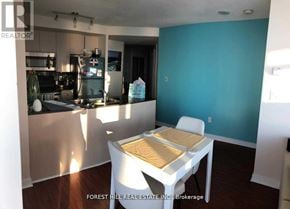 Toronto (Waterfront Communities) condo for rent - A kitchen with a table and chairs in the foreground and a blue wall in the background.