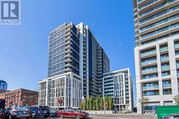 Toronto (Moss Park) condo for rent - A tall building with a glass facade stands in front of a shorter building with a white facade.