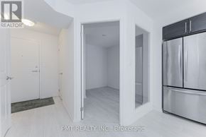 Toronto (Moss Park) condo for rent - A kitchen area with a refrigerator, cabinets, and a doorway leading to another room.