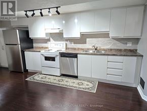 Mississauga (Clarkson) apartment for rent - A kitchen with white cabinets and a black refrigerator.