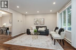 Waterloo apartment for rent - A living room with a black couch, white chairs, and a rug.